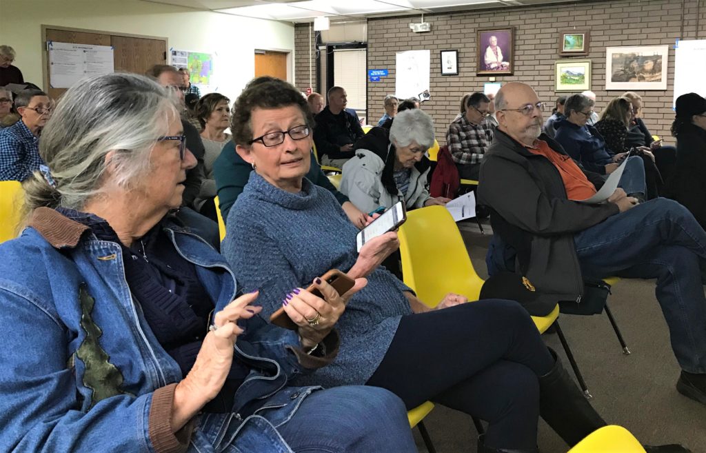 Library patrons use their smartphones to give feedback on possible library sites during one of two community meetings held Oct. 30.