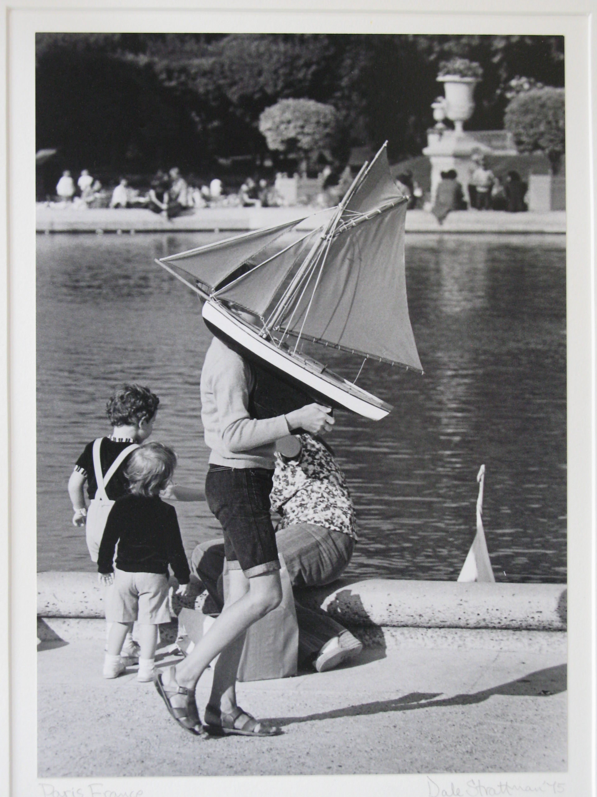 In a photo by Dale Strattman, a boy carries a toy boat in front of a reflecting pool.