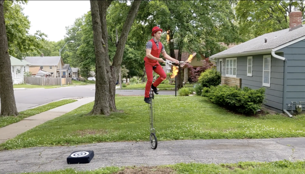 Jason D'Vaude juggles flaming torches while balanced on a four-foot-tall unicycle.