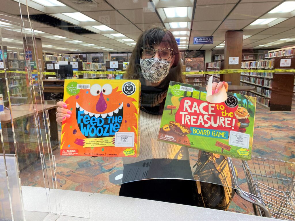 Barbara Bunting holds up two board games she just checked out from the library.