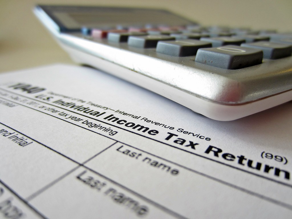 A calculator sits atop a paper IRS 1040 tax form.