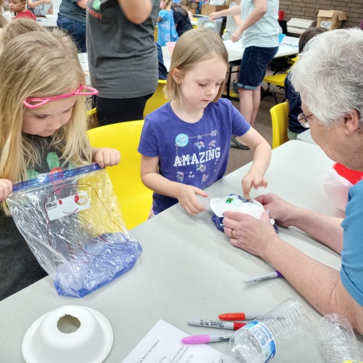 Children participate in a science activity with the help of a grown-up.
